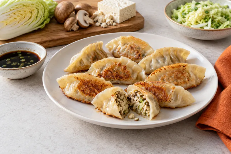 Gevouwen dumplings met een gebakken onderkant en een vulling van tofu, champignons en kool.